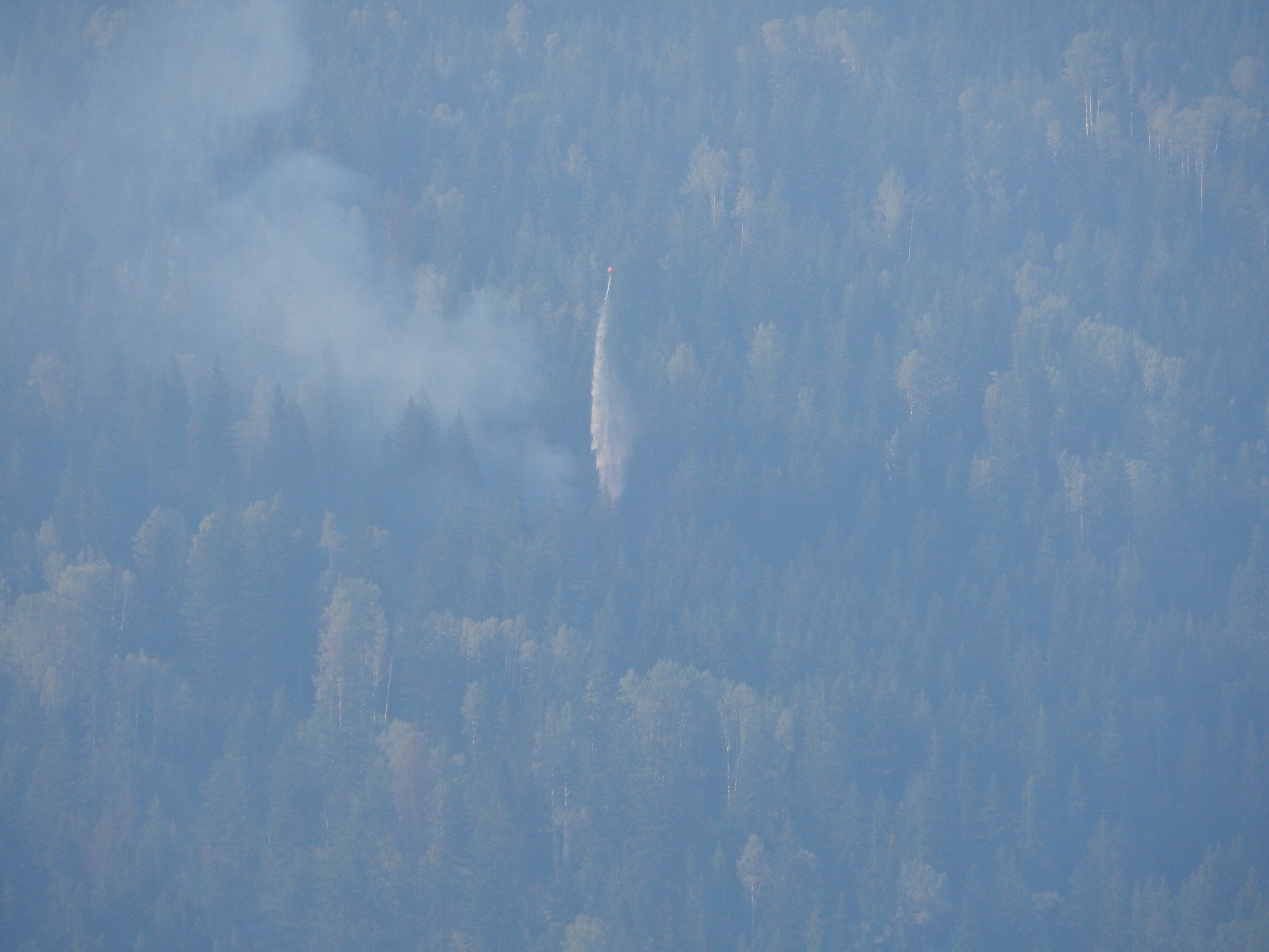 A helicopter drops a load of water on the power line fire north of Balfour, as seen from the Kootenay Lake ferry.