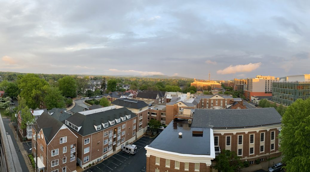 The setting sun illuminates Charlottesville from under the clouds, from the rooftop bar of the Graduate hotel.