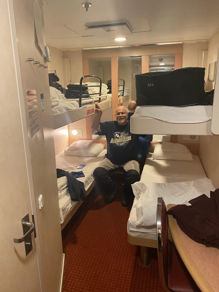 Chuck sits in the aisle in our palatial mansion of a room on the Newfoundland ferry; the door to the left is our bathroom.