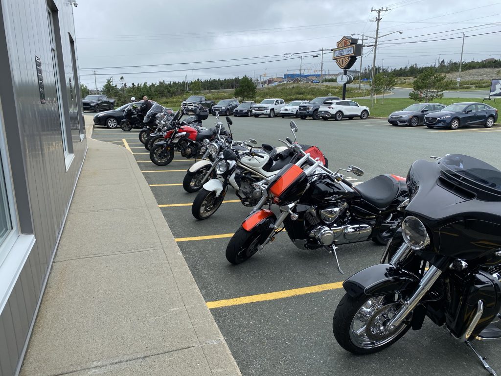 The motorcycle parking area at Rugged Rock Harley-Davidson in St. John’s, Newfoundland. Which two things are not like the others?