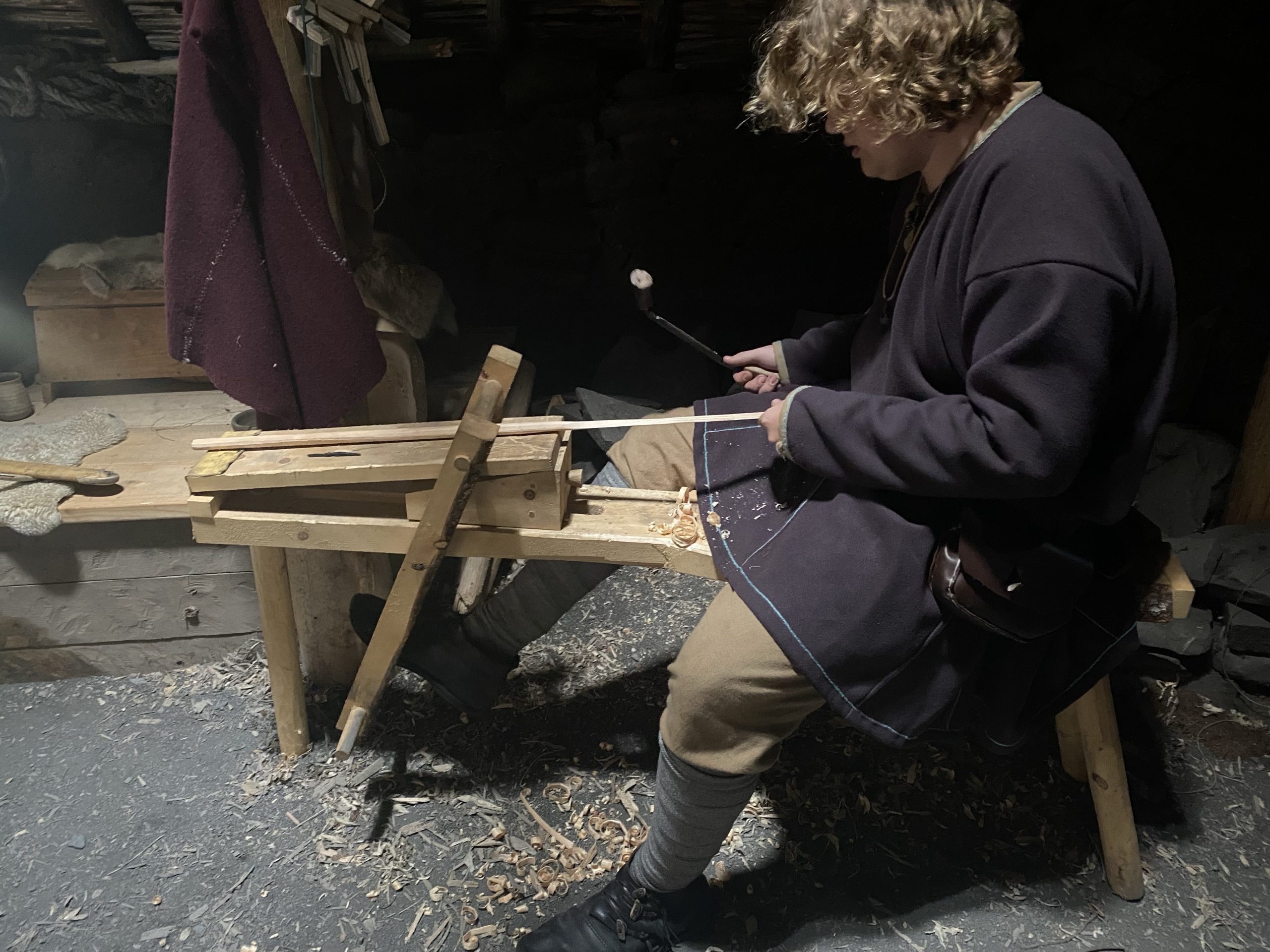 Working a piece of wood on an Norse wood vise in a recreation of a 1,000 year old sod house.