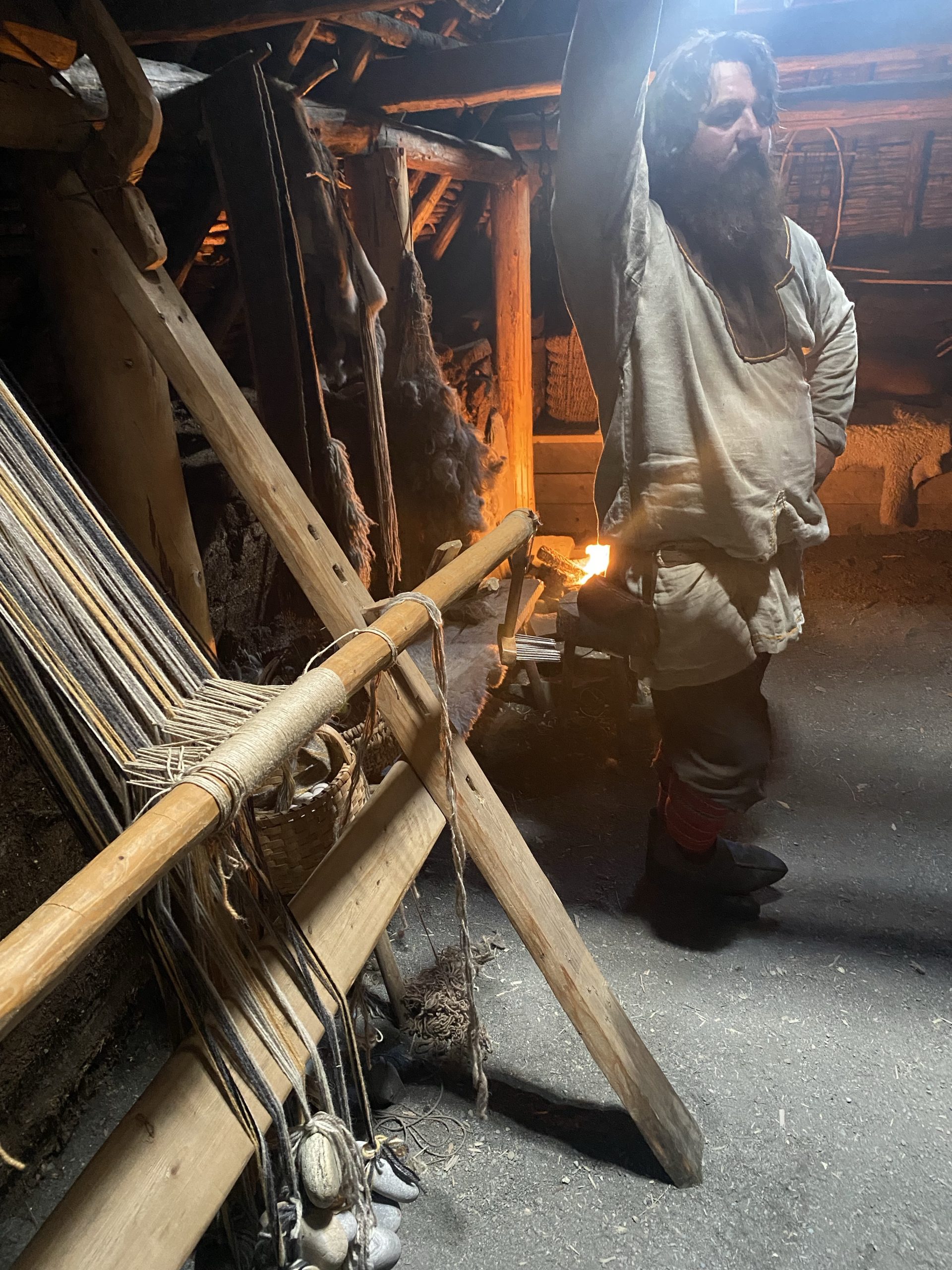 Ragnar (character name) stands behind a loom in the women’s work room in a re-created 1,000 year old Norse sod house.