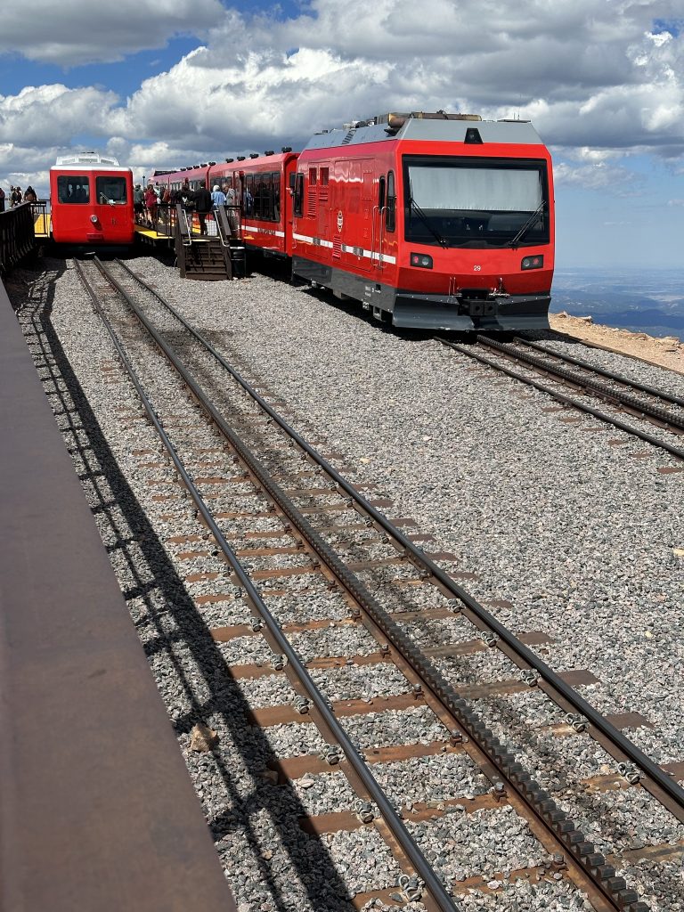 Two cog railway trains (old and new) wait at the top of Pike’s Peak.